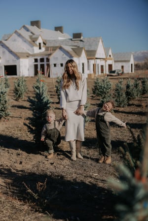 Happy family walks in pine tree field with home construction in background